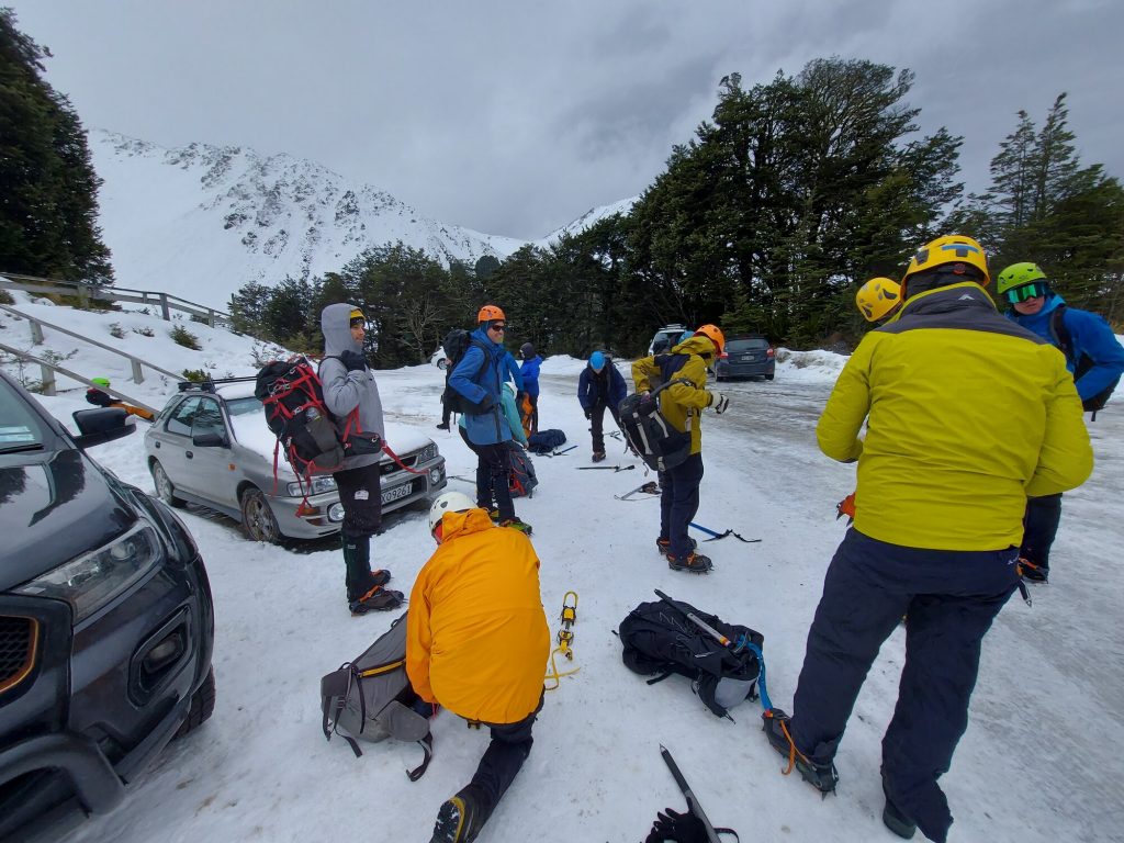 Alpine climbers putting on their gear in a carpark. 