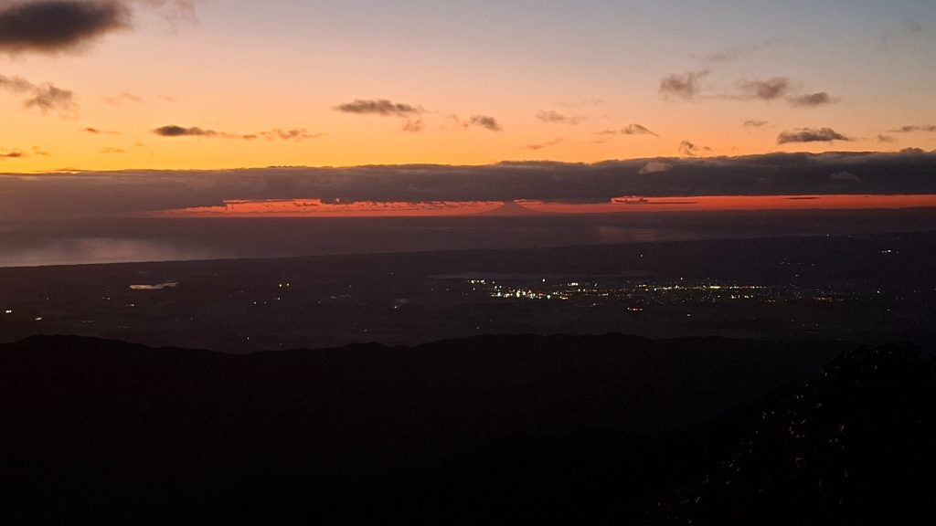 A volcanic cone seen at sunset on the horizon. 